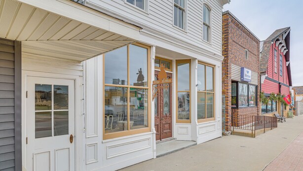 A building with large windows and a door, a brick facade, and a sidewalk.