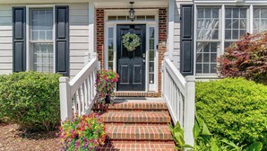 A house with a front porch, a black door with a wreath, and a brick staircase leading up to the entrance. - Fire Pit + Pool Access: Quiet Holly Springs Home (Holly Springs)