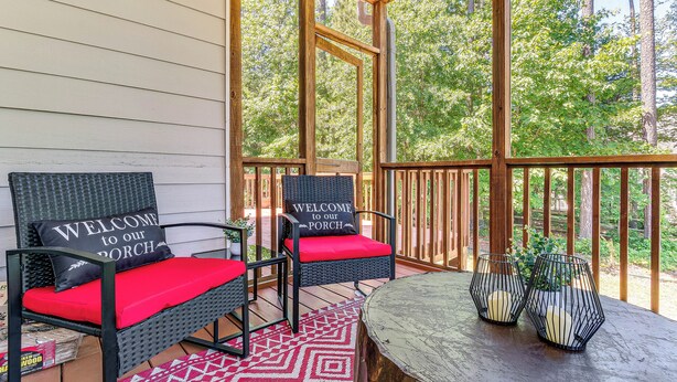 A porch with two wicker chairs, red cushions, and a welcome sign. - Fire Pit + Pool Access: Quiet Holly Springs Home (Holly Springs)