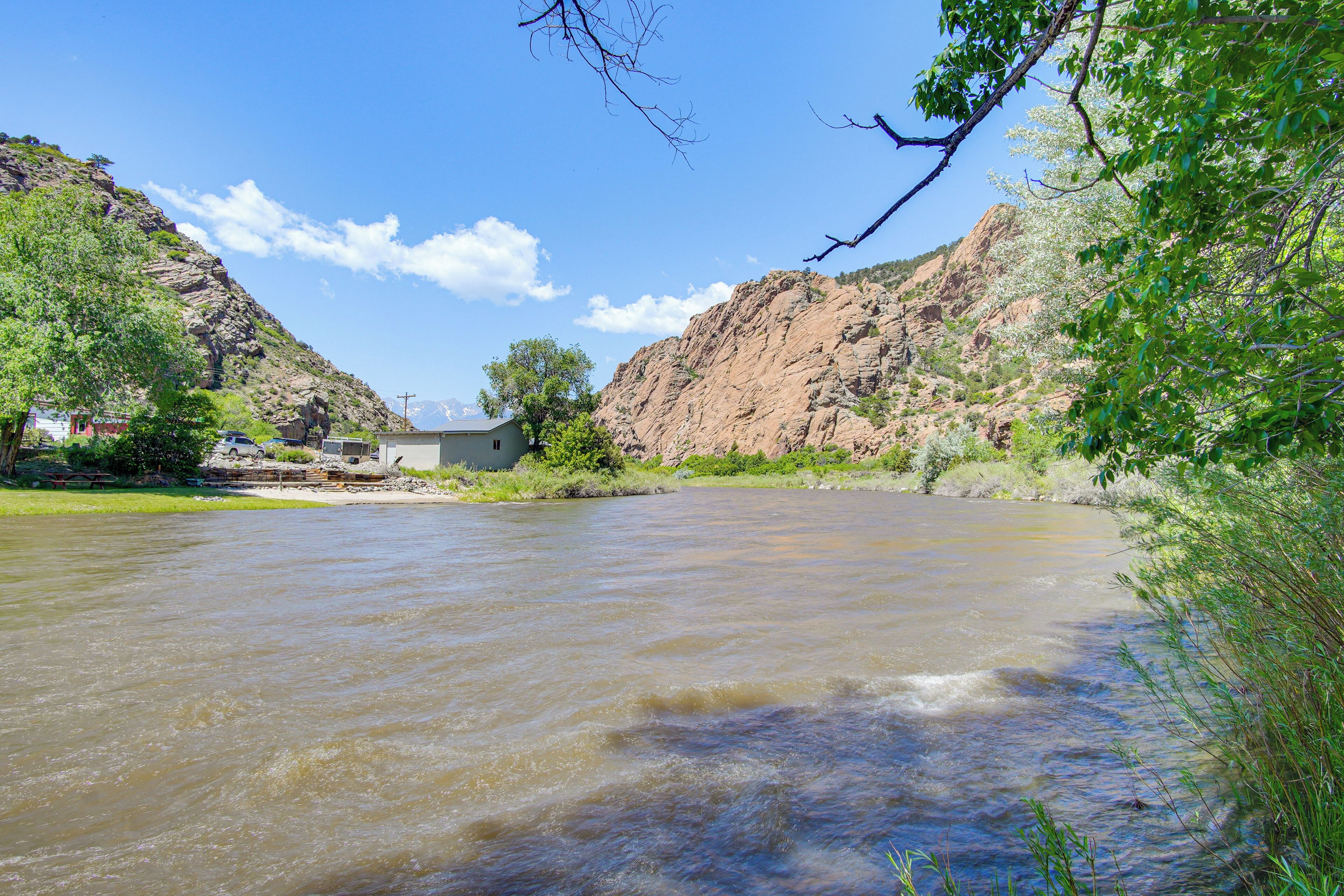 A river flowing through a valley with rocky hills and greenery.