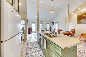 Una cocina amplia con una isla grande, un comedor con candelabro y vistas al salón.