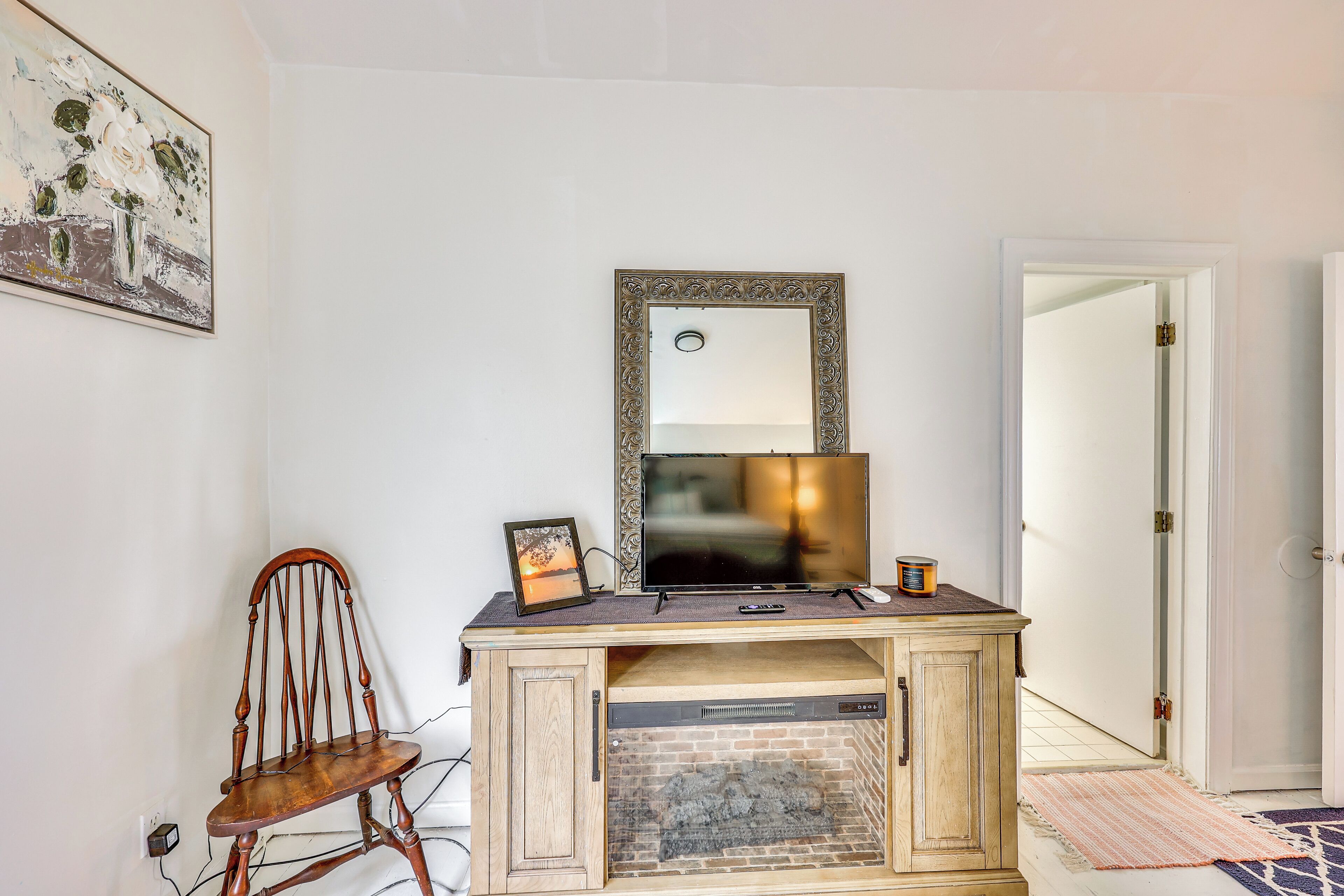A room with a wooden cabinet, a television, a framed picture, and a fireplace.