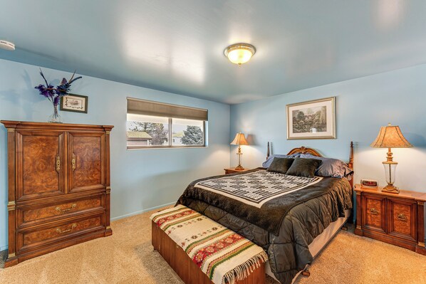 A bedroom with a bed, a wooden cabinet, a window, and two lamps. - Bring a Pet: West Valley City House w/ Grill (West Valley City)