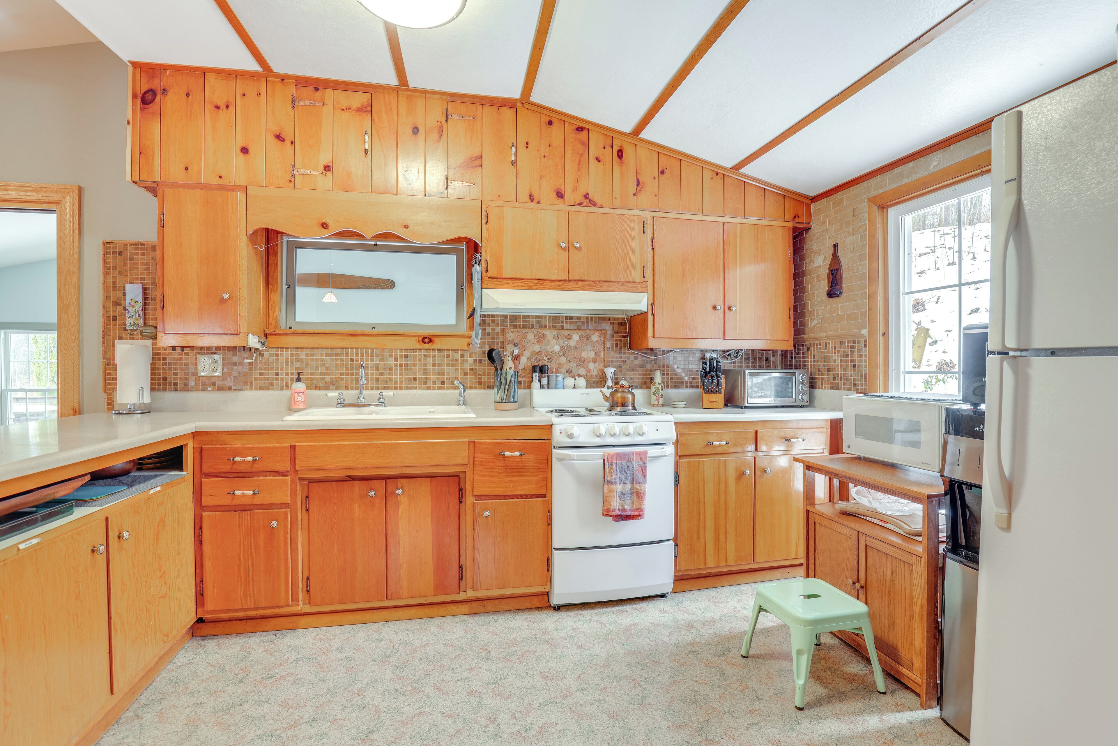 A kitchen with wooden cabinets, a stove, a microwave, and a refrigerator.