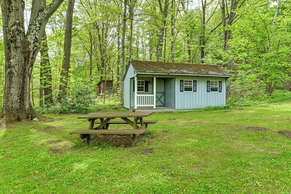 Een klein huisje met een veranda en een picknicktafel in een bebost gebied.