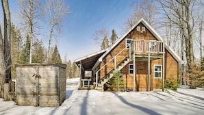 A wooden cabin with a balcony, a staircase, and a snow-covered ground. - Near Lake Huron: Secluded Goetzville Cabin w/ Deck (Goetzville)