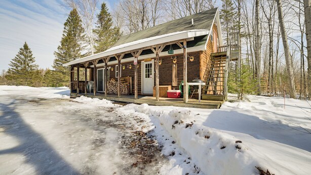 A log cabin with a porch, a fire pit, and a ladder leading to the upper floor. - Near Lake Huron: Secluded Goetzville Cabin w/ Deck (Goetzville)
