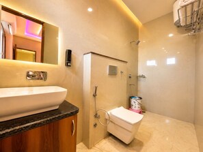 A modern bathroom with a large sink, a shower, and a toilet.