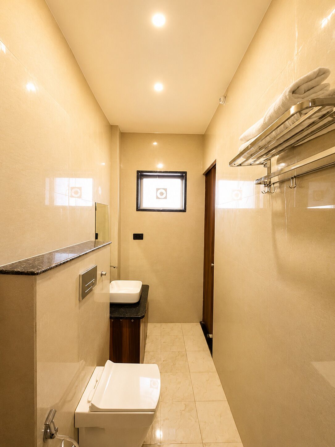 A narrow bathroom with a sink, toilet, and towel rack.
