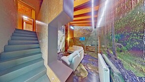 A staircase leading to a living area with a sofa and a mural.