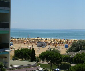 A beach with numerous umbrellas and sun loungers, a clear sky, and a view of the sea. - Comfy Apartment by the sea in Bibione (San Michele al Tagliamento)