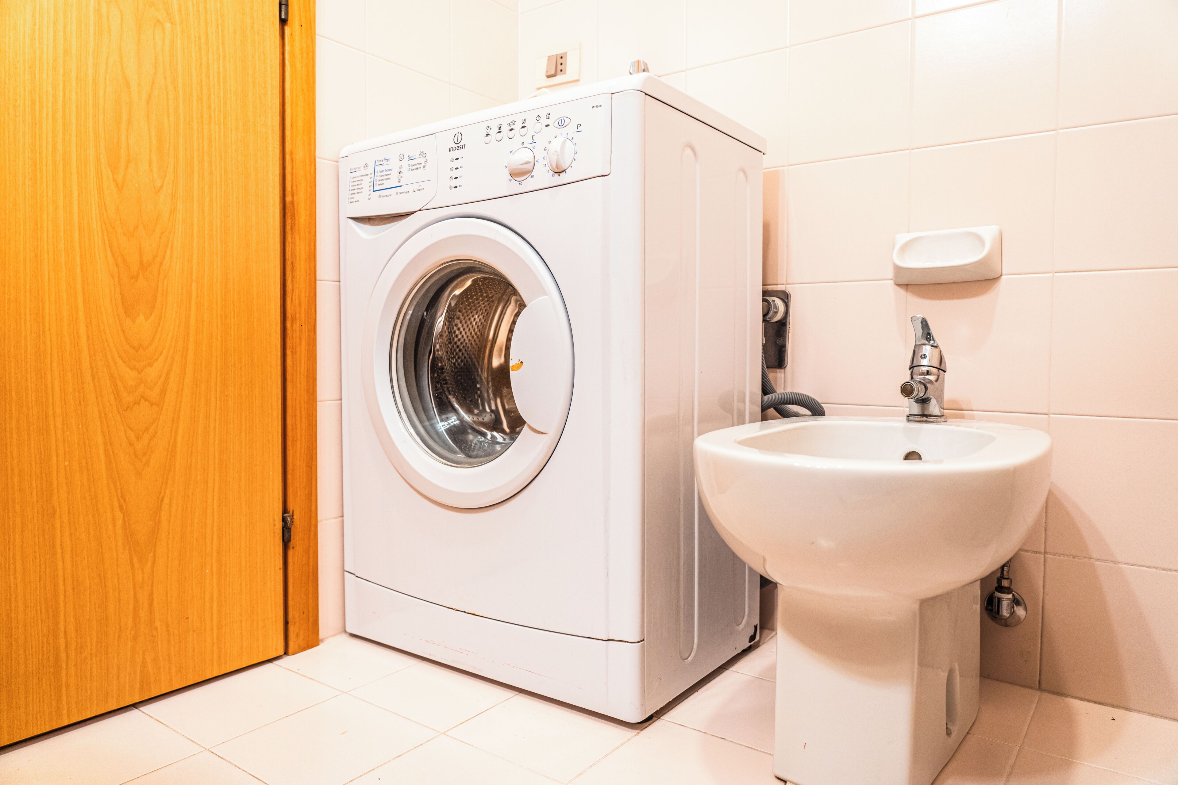 A compact, modern laundry room with a front-loading washing machine and a sink.