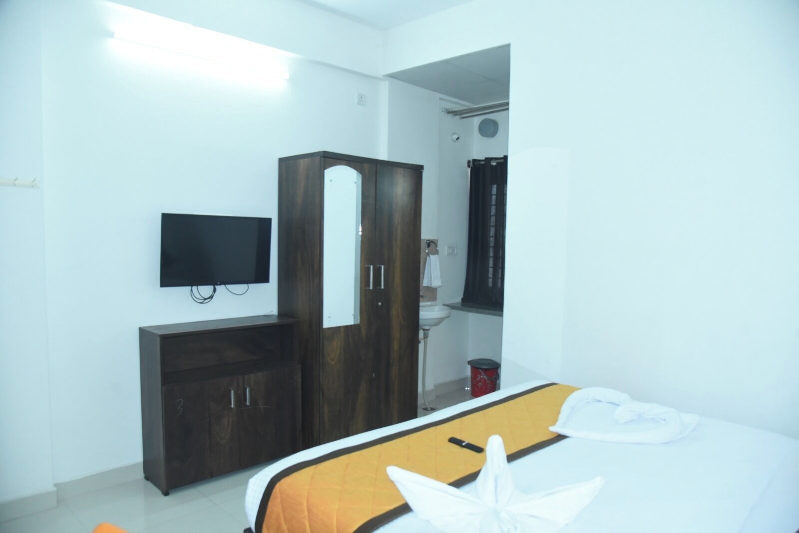 A bedroom with a bed, a wardrobe, a television, and a bathroom visible through an open door.