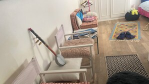 Une pièce avec une chaise blanche, une petite table, un tapis à motifs et un pouf noir à poils longs.