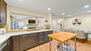 A modern kitchen with dark cabinets, a large island, and a dining area with a table and chairs. - Perfect in the Pines - 38 Aspen Circle (Plumas Eureka)
