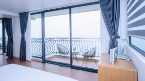 A modern hotel room with a large sliding glass door leading to a balcony with metal railings and two chairs. - Comay Sapa House (Sa Pa)