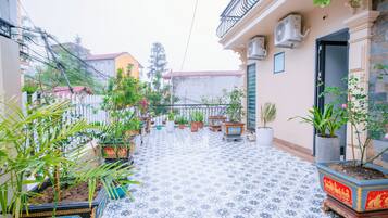 Un patio con plantas en macetas, suelo de baldosas y unidades de aire acondicionado en las paredes.