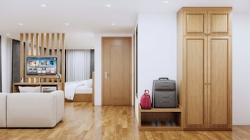 Una habitación de hotel moderna con un armario de madera, una cama, un televisor montado en un panel de madera y un zapatero con una maleta.