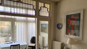 A room with a dining table, chairs, a radiator, a lamp, and artwork on the wall.