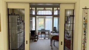 A hallway leading to a dining area with a table and chairs, a bookshelf, and a decorative wall piece.