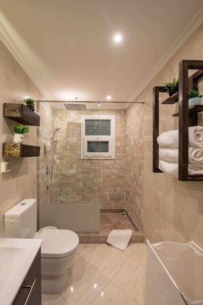 A modern bathroom with a glass-enclosed shower, a toilet, and a sink. - Xuru Stays I Waterfront Designer 2BR - 5 min to Airport (Cairo)