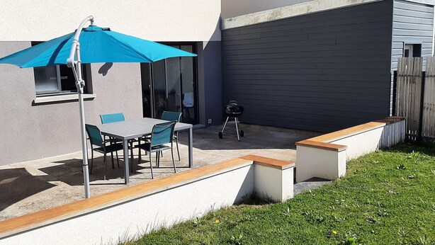 Une terrasse avec une table et des chaises, un parasol bleu et un banc en bois.