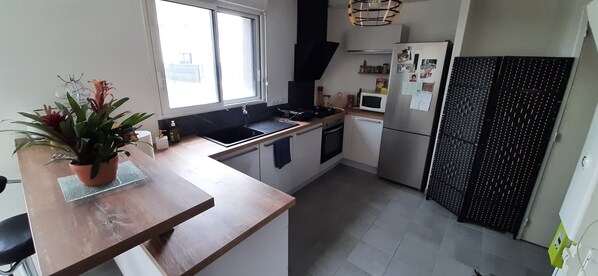Une cuisine moderne dotée d’un plan de travail en bois, d’un évier, d’une cuisinière, d’un four à micro-ondes et d’un réfrigérateur.
