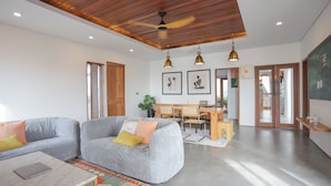 A modern living room with a grey sofa, wooden ceiling, and pendant lighting. - Lorn Villa (Penida Island)