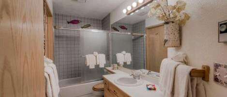 A modern bathroom with a shower, a sink, and a vanity.