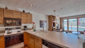 Une cuisine moderne avec des meubles en bois, des appareils en acier inoxydable et un grand îlot central doté d’un lave-vaisselle.