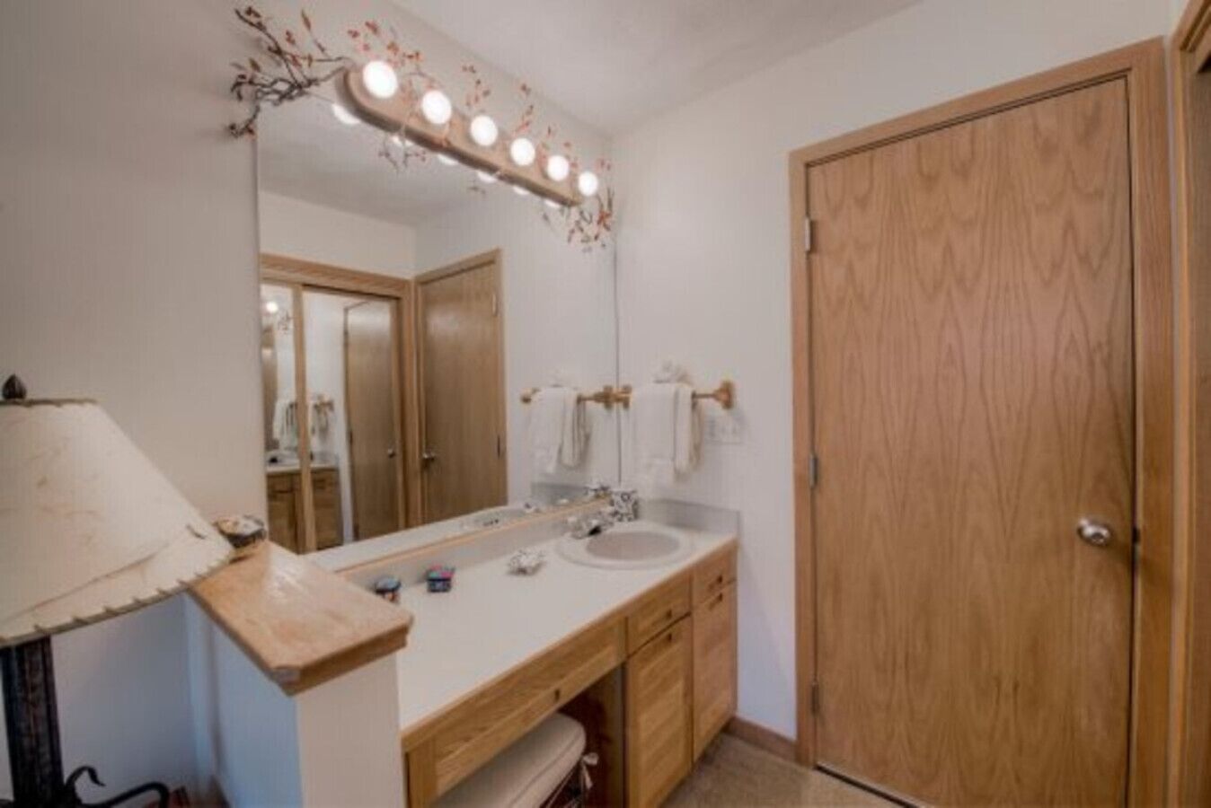 Une salle de bain avec un meuble-lavabo, un évier, un miroir et une porte en bois.