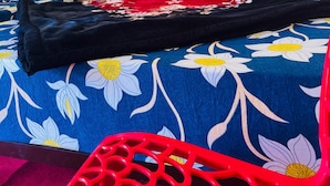 A bed with a floral bedspread, a red blanket, and a red chair. - Sunrise Resort (Shivpuri)