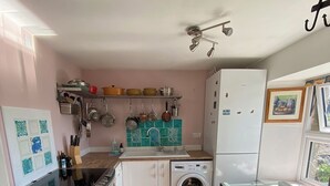 A compact kitchen with a washing machine, a dining table, and a ceiling fan. - Idyllic Hebridean Island Retreat (Kintra)