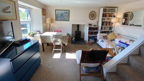 A cozy living room with a fireplace, a bookshelf, a dining area, and a TV. - Idyllic Hebridean Island Retreat (Kintra)