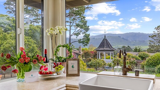 Una cocina con un ventanal grande que ofrece una vista panorámica de un jardín y montañas.