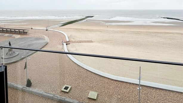 A beach view from a balcony with a curved walkway, a lifeguard tower, and a sandy beach. - Apartment in Wenduine With Stunning Sea Views (De Haan)