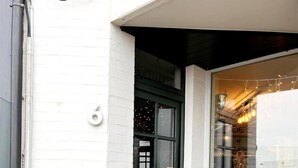 A storefront with a green door, a white brick wall, and a window displaying plants. - Apartment in Wenduine With Stunning Sea Views (De Haan)