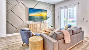 A modern living room with a sofa, armchair, and a TV mounted on a geometric wall.