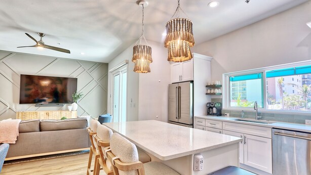 A modern kitchen with a central island, stainless steel appliances, and pendant lighting.