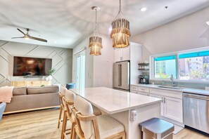 A modern kitchen with a central island, stainless steel appliances, and pendant lighting.