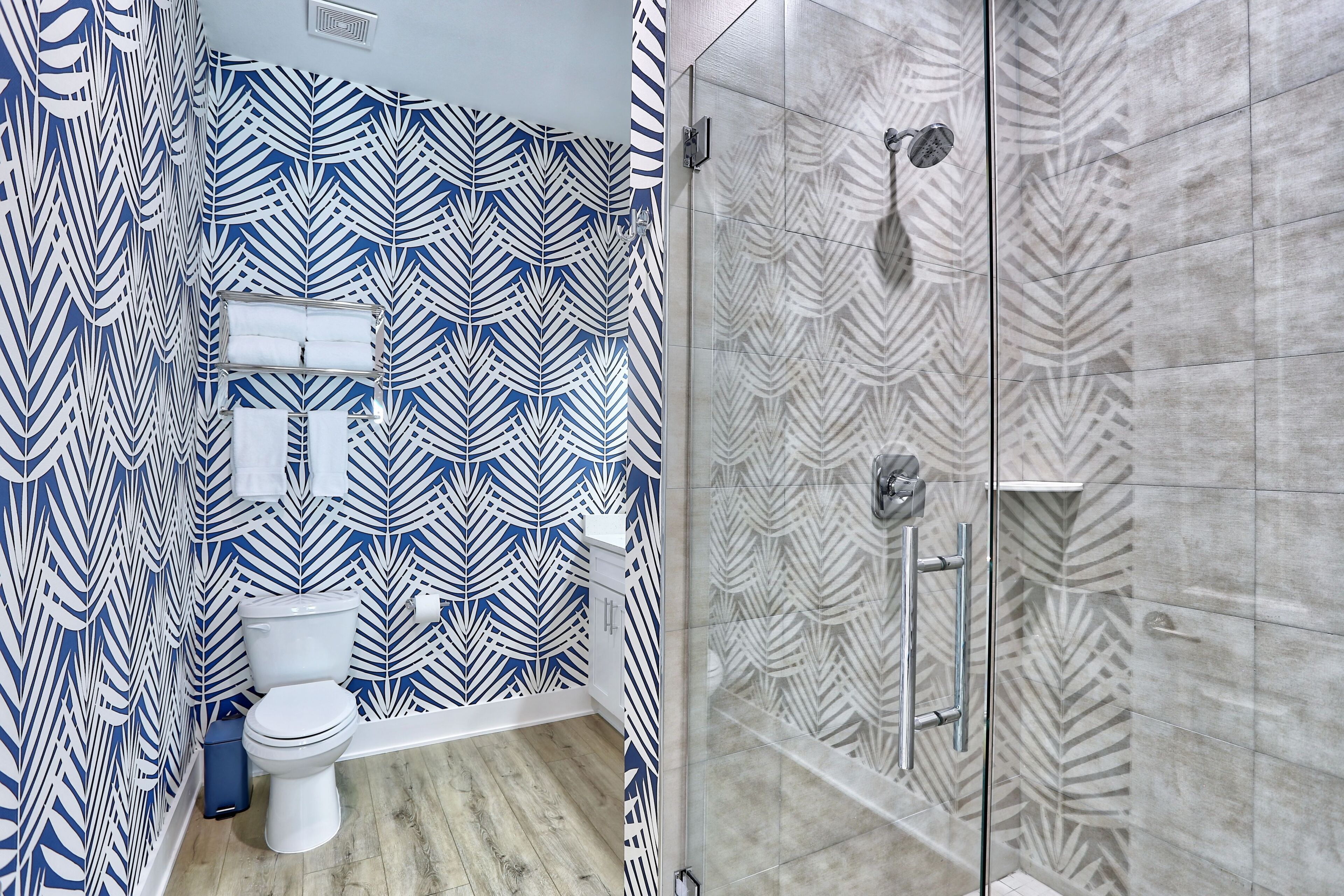 Un bagno con parete decorata, un WC, un lavandino e uno spazio doccia.