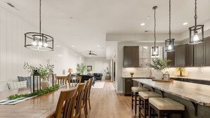 A spacious kitchen with a long island, dark cabinets, and pendant lighting. - Twice Charmed 8 Bedroom Townhouse (Hurricane)