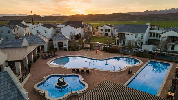 A residential area with a swimming pool surrounded by houses, a patio area, and a view of mountains in the background. - Twice Charmed 8 Bedroom Townhouse (Hurricane)