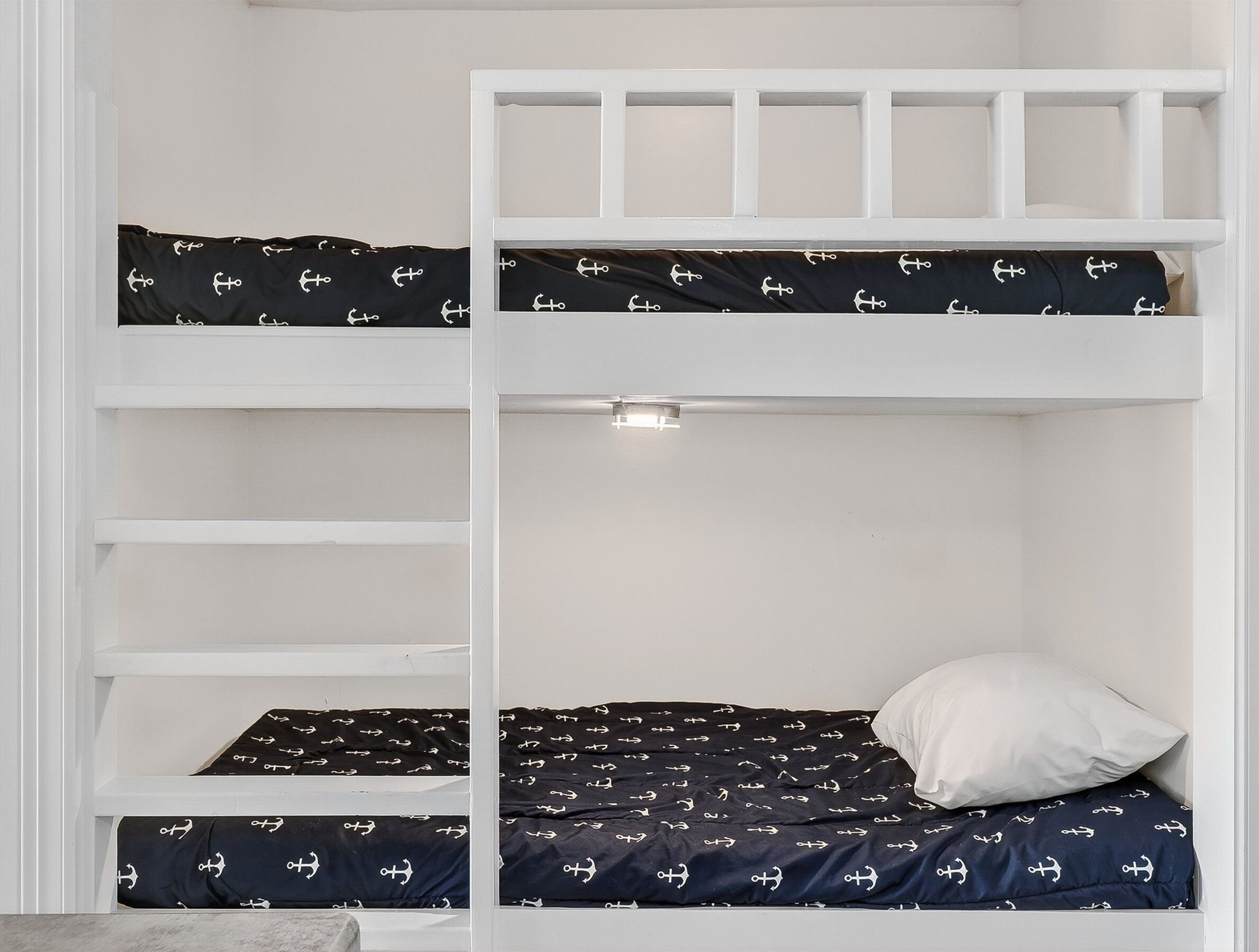 A bunk bed with two levels, each with a black mattress featuring a white anchor pattern.