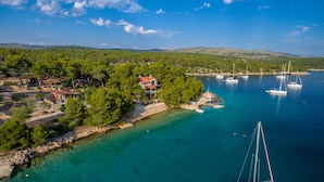 An aerial view of a coastal area with a marina, clear turquoise waters, and a cluster of houses surrounded by greenery. - Hidden Heaven Private Resort - Heated Pool (Milna)