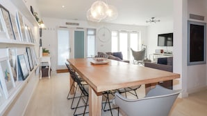 A modern kitchen with a wooden table, black chairs, and a pendant light. - Tincroft (Truro)