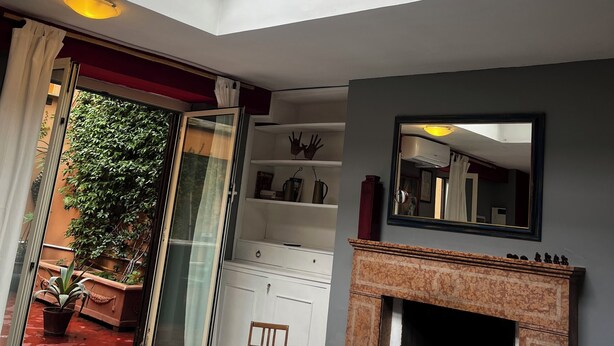 A living room with a glass ceiling, a fireplace, and a view of greenery outside. - Chic studio with AC and WiFi in phenomenal Roma (Roma)
