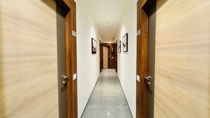 Um corredor com portas de madeira em ambos os lados e chão de azulejos.