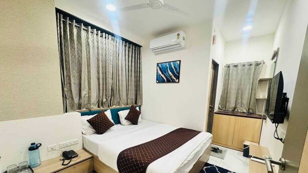 Quarto de hotel moderno com cama, mesa de cabeceira e televisão.