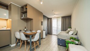 A modern apartment with a dining area, kitchenette, and a bedroom with a bed and a small side table. - Modern 1Bedroom,1 bathroom,Terrace,Wash/Dry and WiFi 8min MetroL5 Santiago (Santiago)